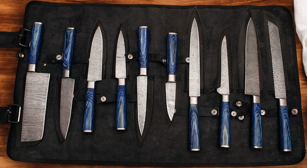 Set of handmade Damascus knives displayed in a leather roll.
