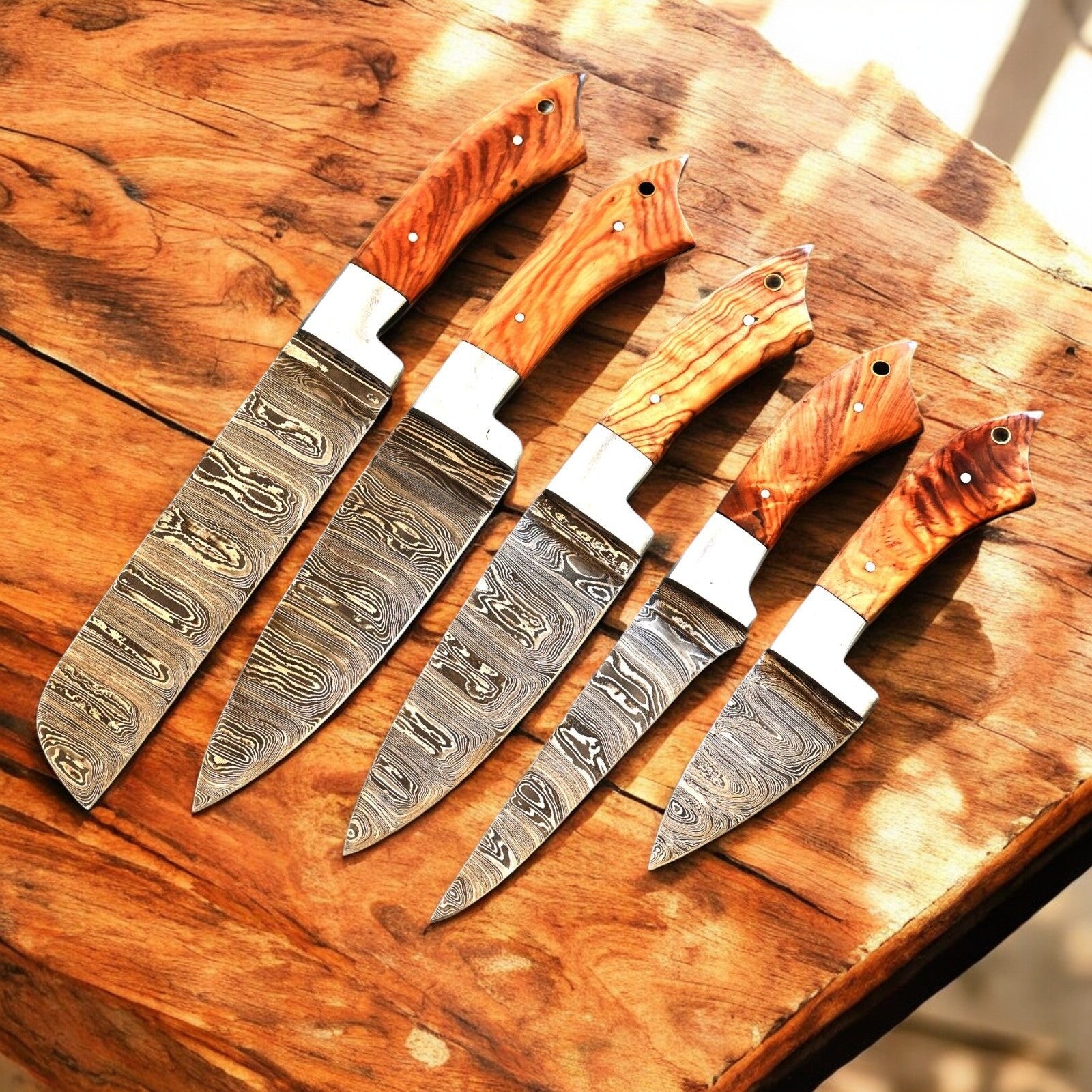 Full view of the custom kitchen knives set laid on a wooden table.
