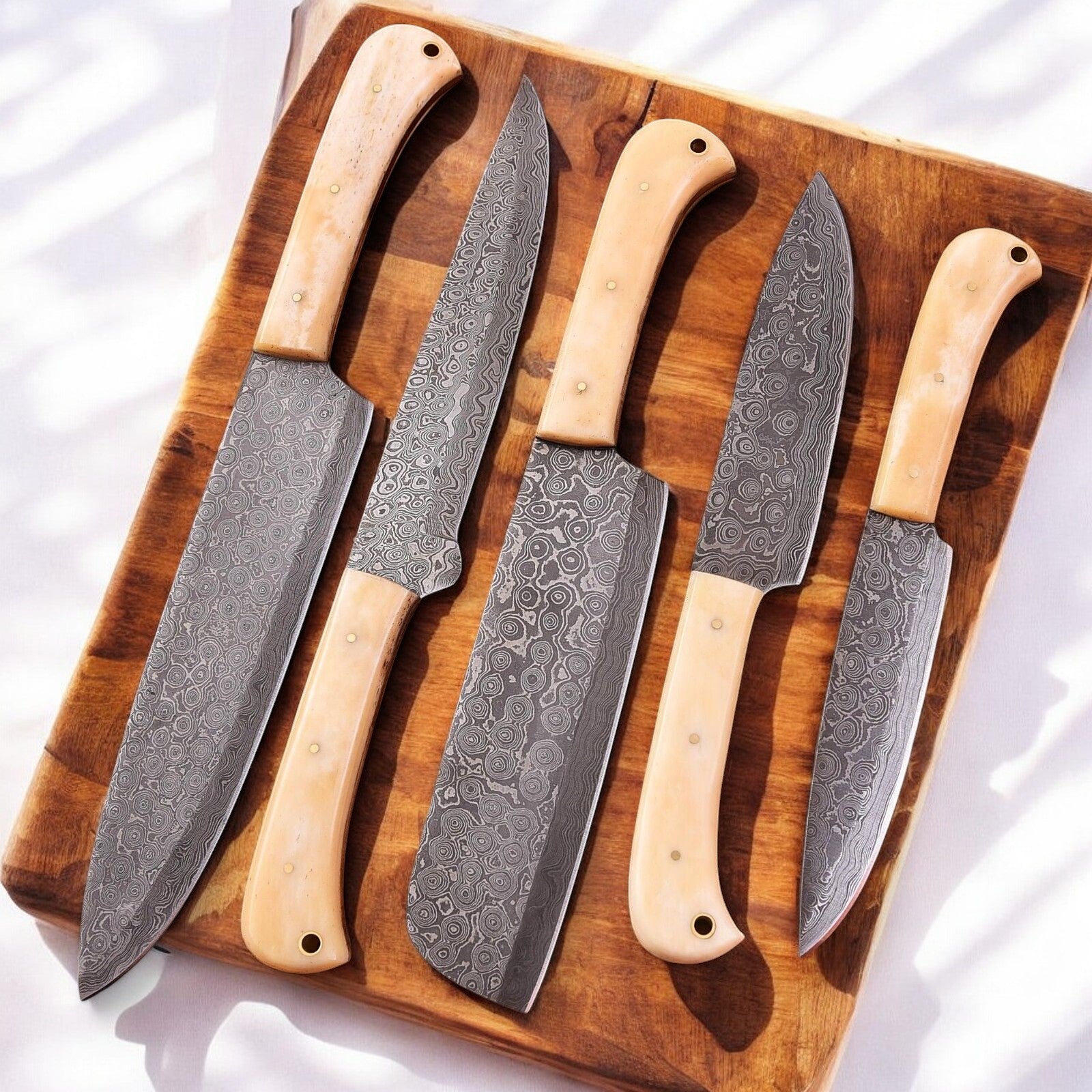 Bone-handled chef knife displayed on a wooden cutting board.
