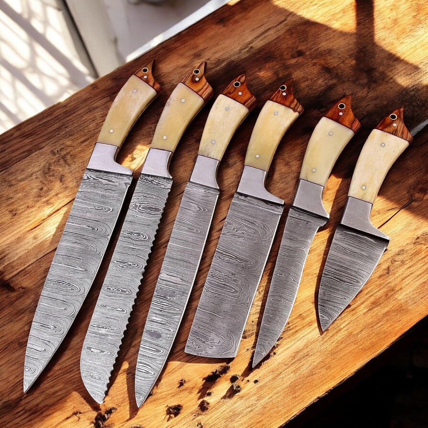 Handmade Damascus kitchen knives displayed on a wooden counter.
