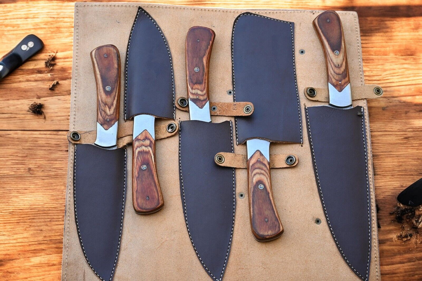 Full view of custom kitchen knives with elegant handles and leather roll.
