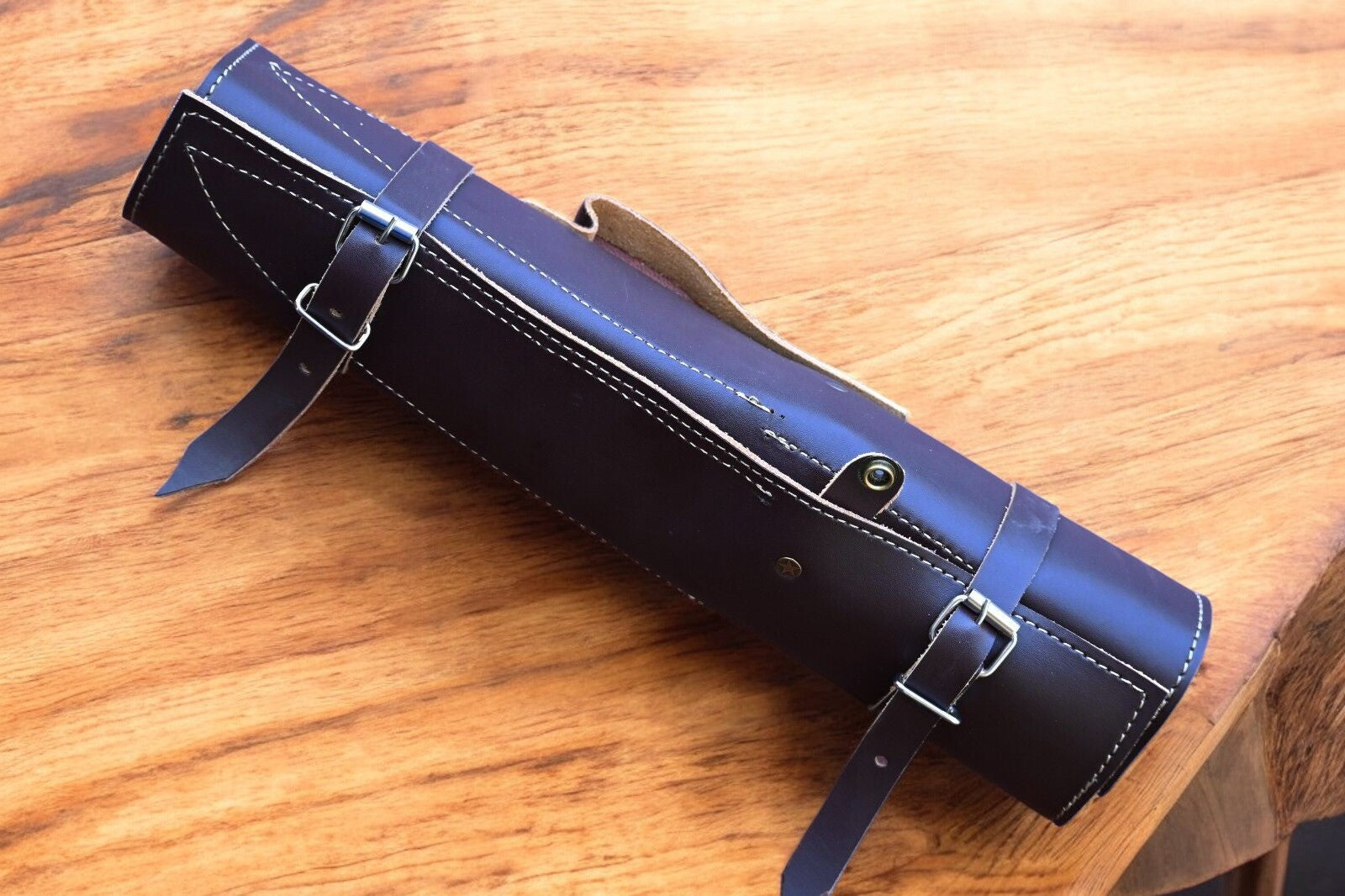 Custom kitchen knife set displayed on a leather roll.
